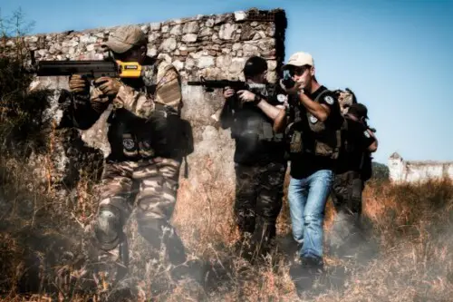 a group of guys playing airsoft outside
